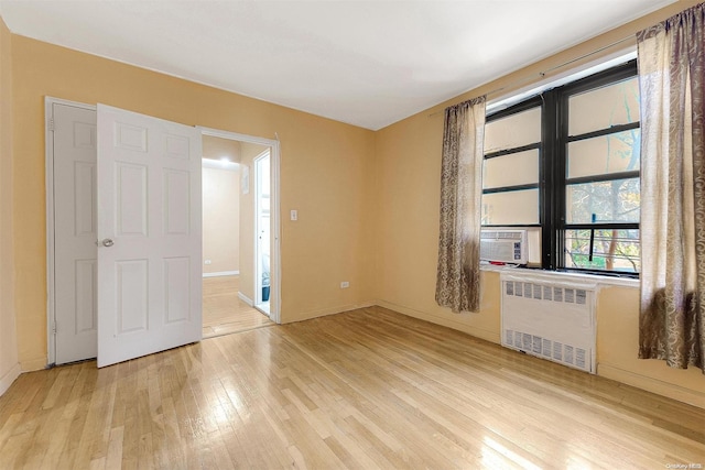 empty room featuring light hardwood / wood-style floors, radiator, and cooling unit