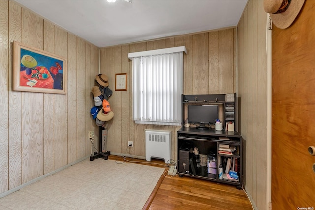 miscellaneous room featuring wood walls, light wood-type flooring, and radiator heating unit