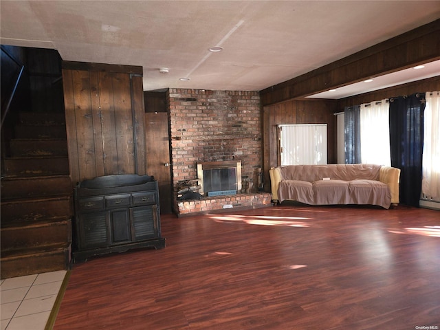 unfurnished living room with a brick fireplace, wooden walls, and dark hardwood / wood-style floors