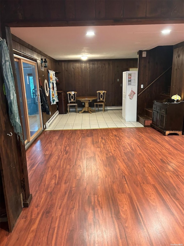 unfurnished dining area with light hardwood / wood-style flooring, a baseboard radiator, and wooden walls