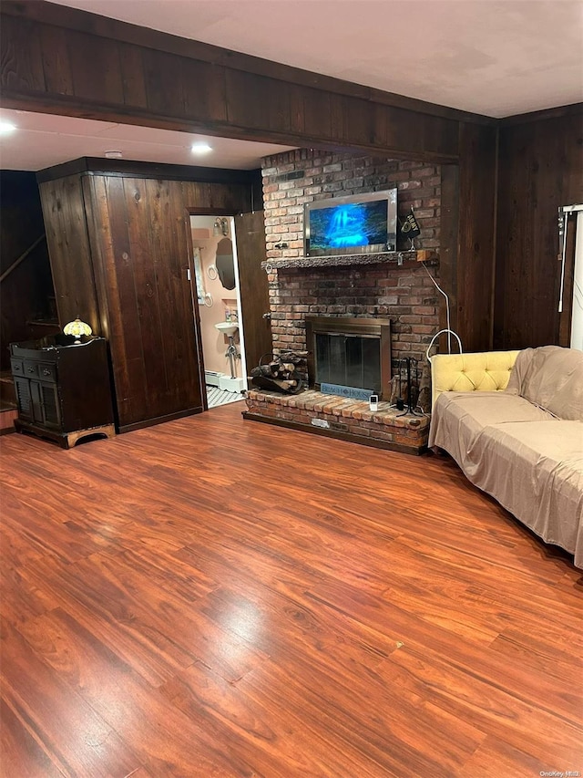 living room with hardwood / wood-style flooring, a fireplace, and wooden walls