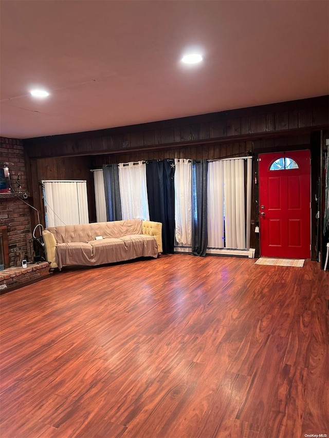 interior space with a fireplace, hardwood / wood-style flooring, baseboard heating, and wood walls