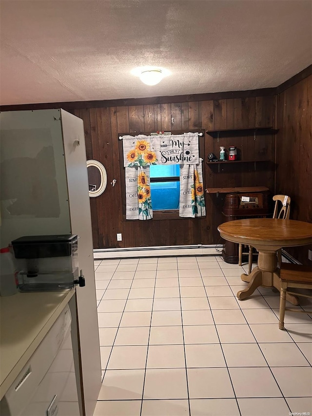 dining room with wood walls, a textured ceiling, and light tile patterned floors