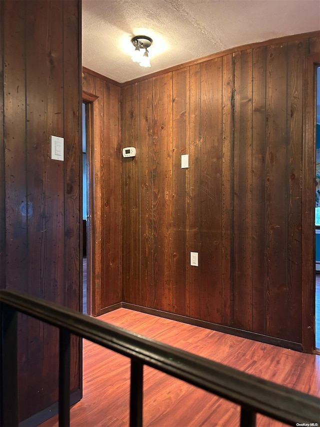 interior space with wooden walls, wood-type flooring, and a textured ceiling