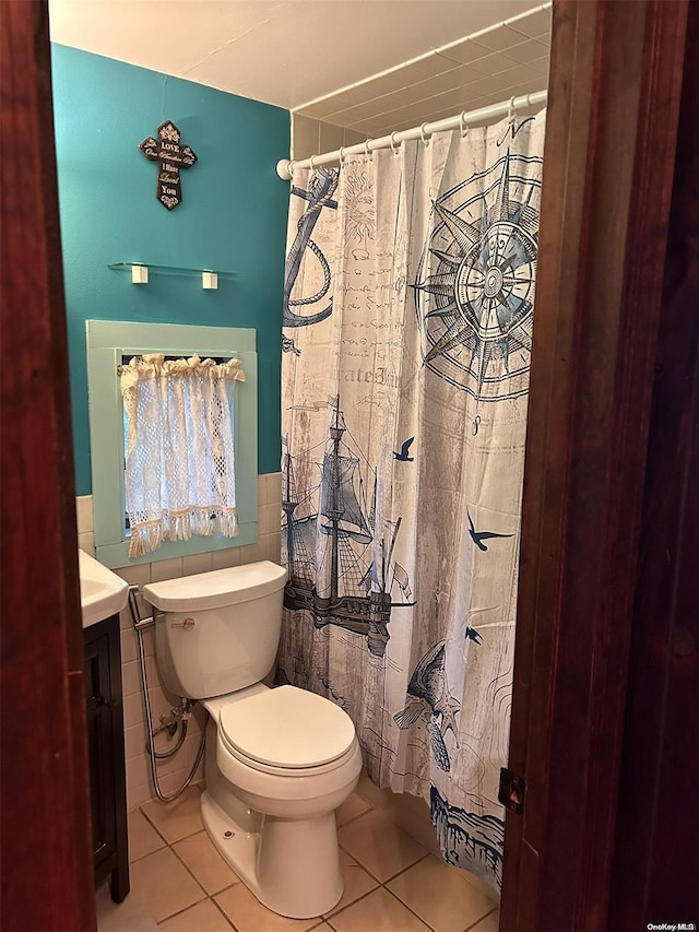 bathroom with tile patterned flooring, vanity, toilet, and tile walls