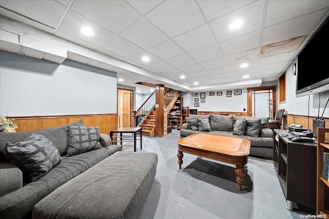 living room featuring a drop ceiling and wooden walls