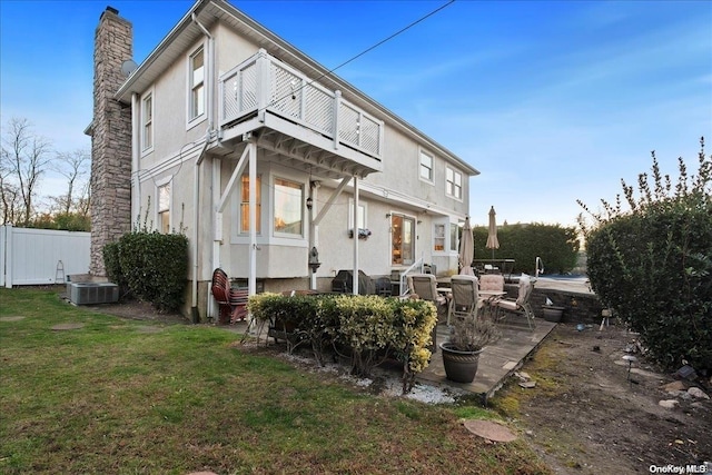 back of property with a lawn, a balcony, a patio, and central AC unit