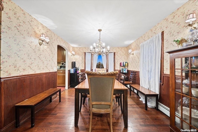 dining room with baseboard heating, wood walls, dark hardwood / wood-style floors, and an inviting chandelier