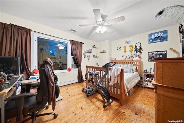 bedroom featuring ceiling fan, a baseboard heating unit, and light hardwood / wood-style flooring