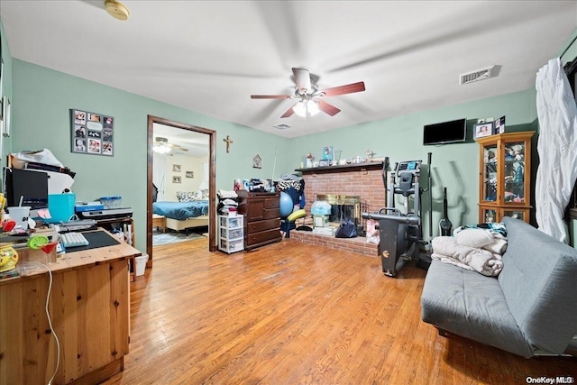 office area featuring ceiling fan, a fireplace, and wood-type flooring