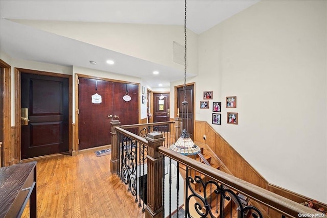 hallway with light wood-type flooring and vaulted ceiling