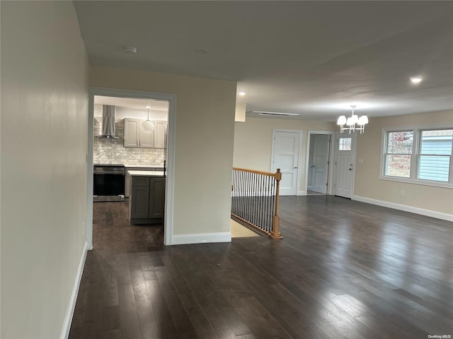 unfurnished living room featuring an inviting chandelier and dark hardwood / wood-style floors