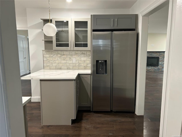 kitchen featuring pendant lighting, gray cabinets, dark hardwood / wood-style floors, light stone counters, and stainless steel fridge with ice dispenser