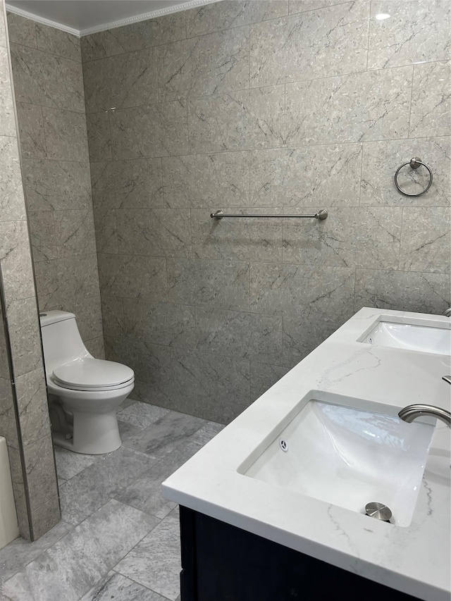 bathroom with tile walls, vanity, crown molding, and toilet