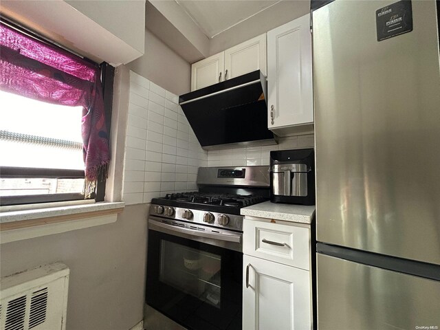 kitchen featuring appliances with stainless steel finishes, extractor fan, white cabinets, and tasteful backsplash