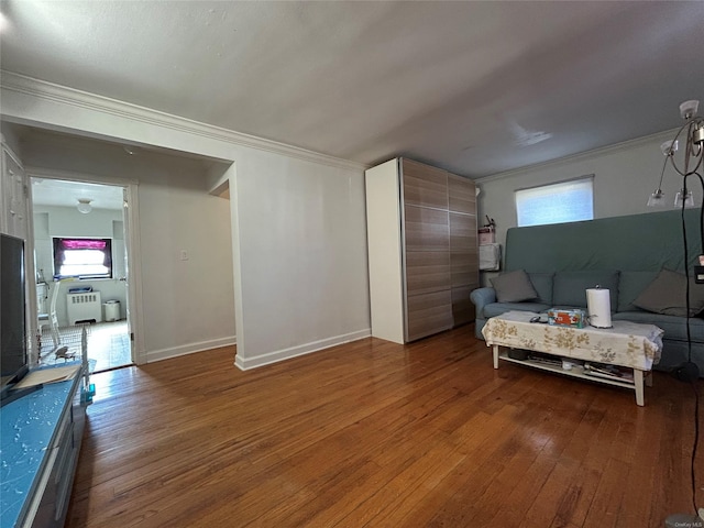 living area featuring wood-type flooring, crown molding, and baseboards