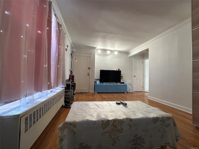 interior space with baseboards, crown molding, radiator heating unit, and wood finished floors