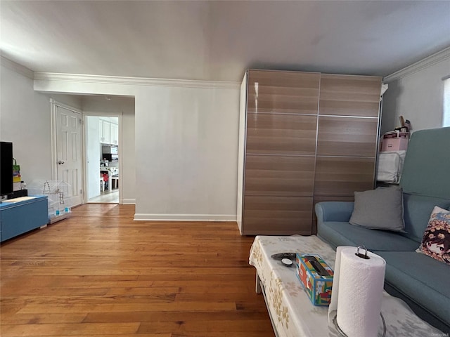 living room with crown molding, baseboards, and wood finished floors