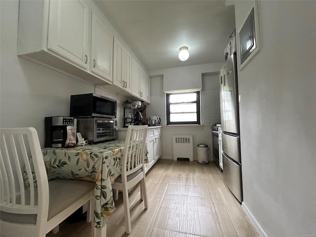 13 W Mill Dr Unit 3A, Great Neck, NY 11021 - kitchen featuring radiator, white cabinetry, freestanding refrigerator, and light countertops