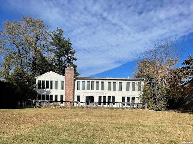 back of house featuring a deck and a lawn