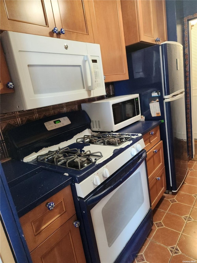 kitchen with white appliances and dark tile patterned flooring