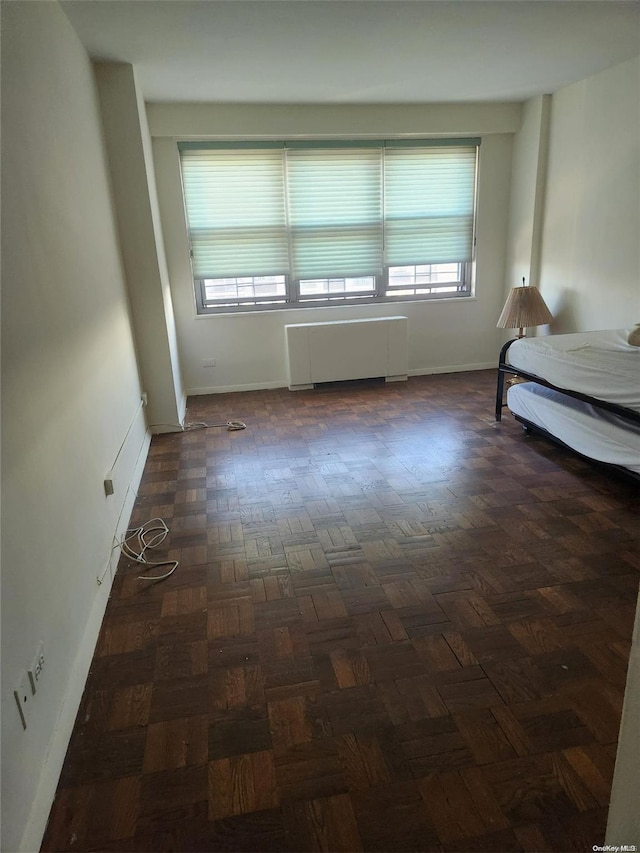 unfurnished bedroom featuring radiator and multiple windows