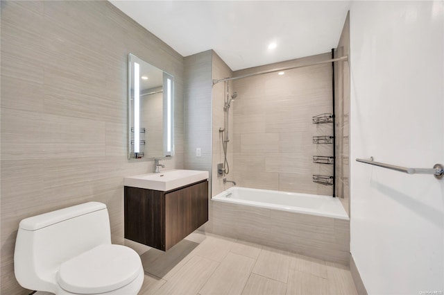 full bathroom featuring tile walls, vanity, tiled shower / bath combo, and toilet