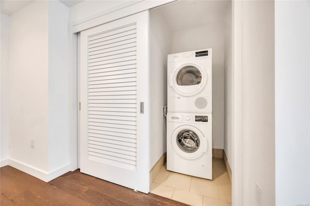 clothes washing area with wood-type flooring and stacked washing maching and dryer