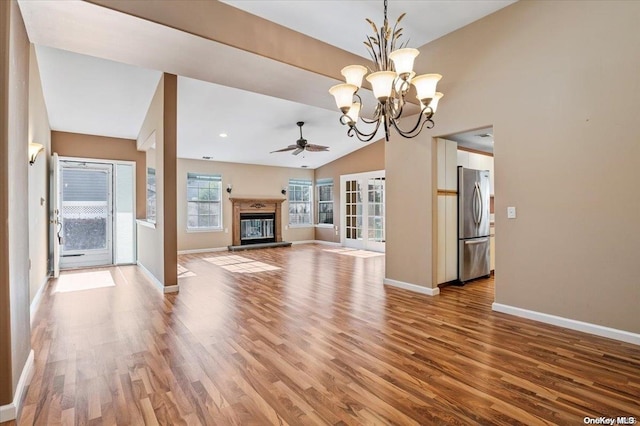 unfurnished living room with ceiling fan with notable chandelier, lofted ceiling, and light wood-type flooring