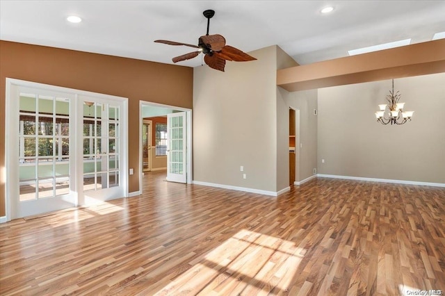 unfurnished living room featuring ceiling fan with notable chandelier, light wood-type flooring, and lofted ceiling