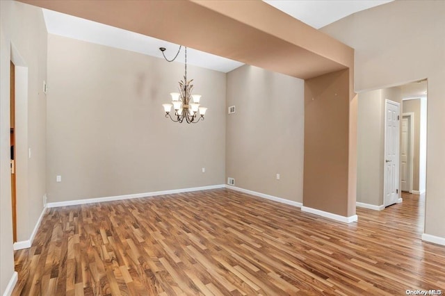 unfurnished room with hardwood / wood-style flooring and a notable chandelier