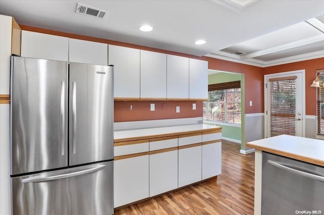 kitchen with light hardwood / wood-style floors, white cabinetry, ornamental molding, and appliances with stainless steel finishes