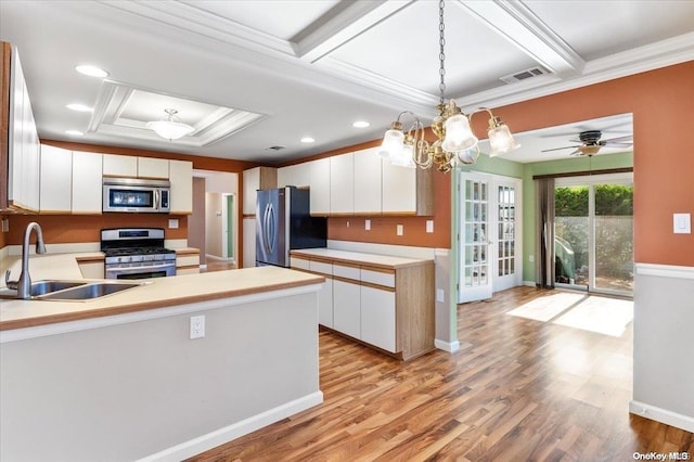 kitchen with white cabinetry, sink, decorative light fixtures, appliances with stainless steel finishes, and light wood-type flooring