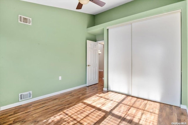 unfurnished bedroom featuring hardwood / wood-style flooring, ceiling fan, and a closet