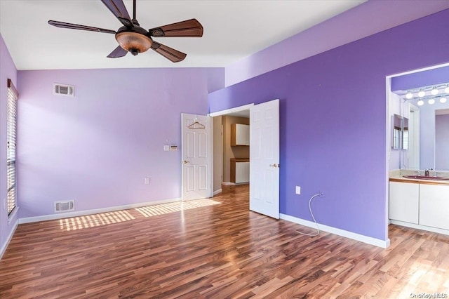 unfurnished bedroom featuring ensuite bathroom, sink, vaulted ceiling, ceiling fan, and wood-type flooring