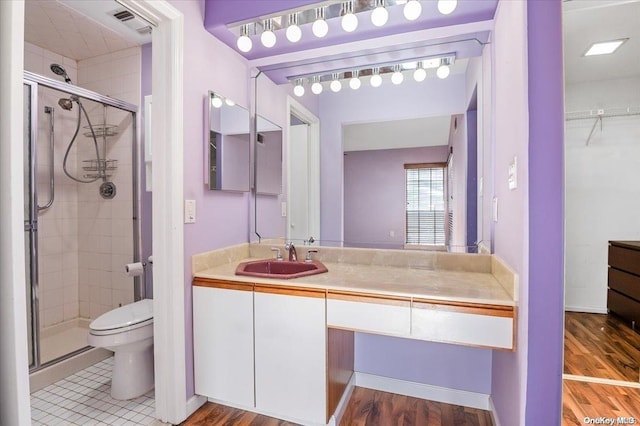 bathroom featuring hardwood / wood-style floors, vanity, a shower with shower door, and toilet