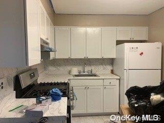 kitchen featuring white cabinets, white fridge, and sink