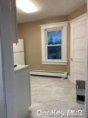 interior space with baseboard heating, white cabinets, and white fridge