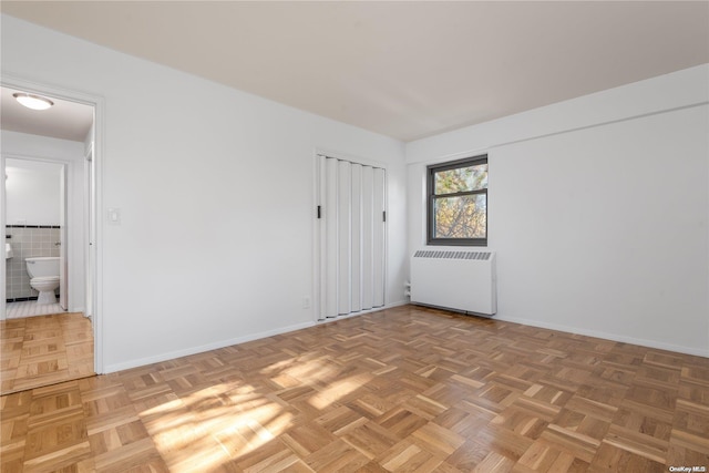 spare room with radiator heating unit and parquet flooring