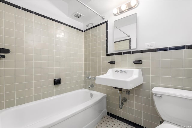 full bathroom with sink, tiled shower / bath combo, tile patterned floors, toilet, and tile walls