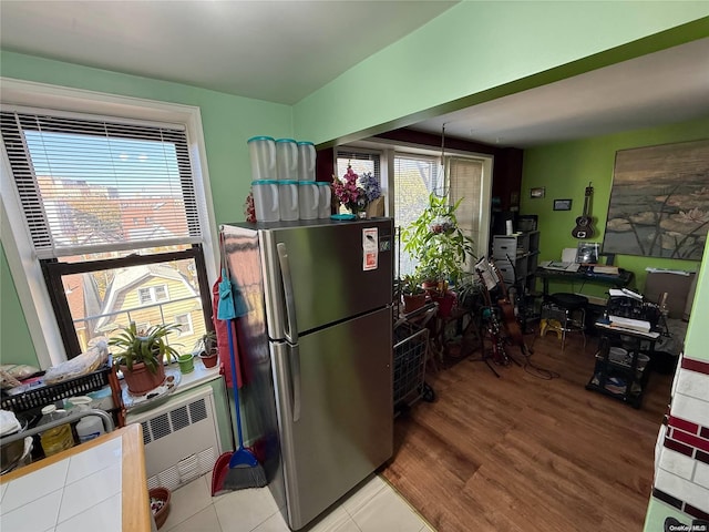 kitchen with radiator, stainless steel fridge, plenty of natural light, and wood-type flooring