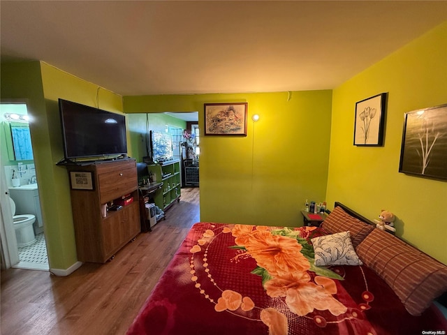 bedroom with hardwood / wood-style flooring and connected bathroom