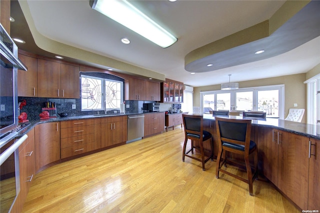 kitchen with decorative backsplash, a healthy amount of sunlight, light wood-type flooring, and stainless steel appliances