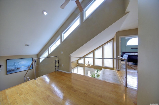 bonus room featuring a wealth of natural light, light hardwood / wood-style flooring, a towering ceiling, and ceiling fan with notable chandelier