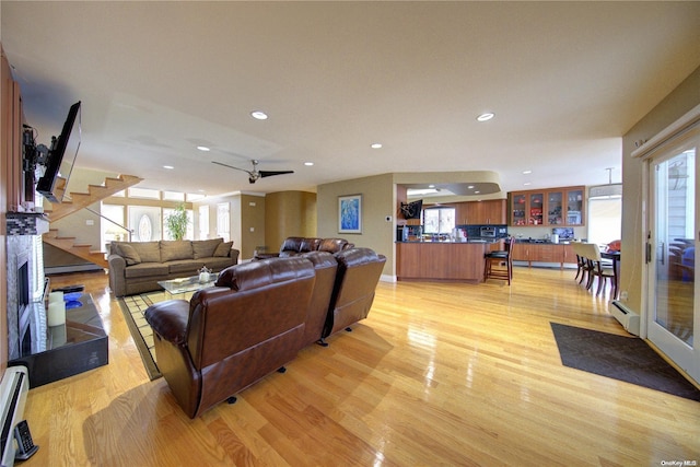 living room featuring ceiling fan, a baseboard heating unit, and light hardwood / wood-style floors