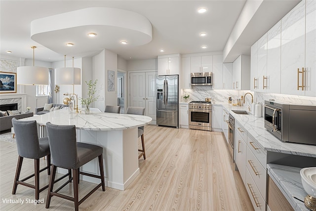 kitchen featuring sink, appliances with stainless steel finishes, hanging light fixtures, white cabinets, and a kitchen island