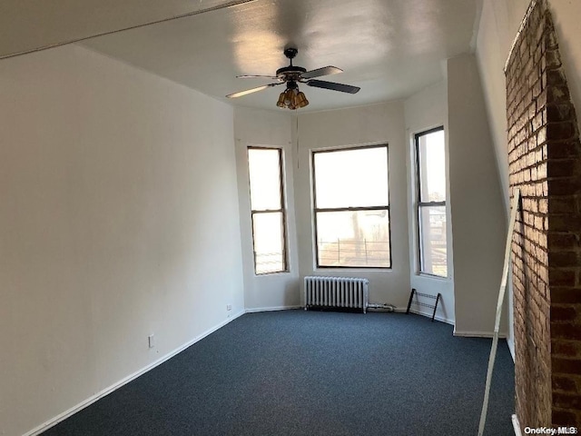 carpeted spare room with ceiling fan and radiator