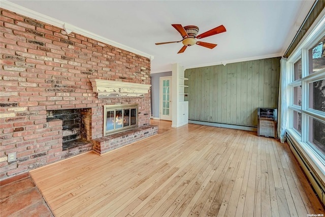 unfurnished living room with a fireplace, wood-type flooring, baseboard heating, and ornamental molding