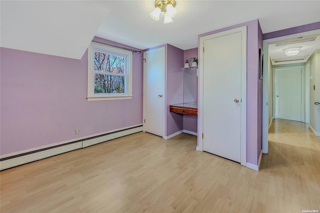 unfurnished bedroom featuring light wood-type flooring, baseboard heating, and a closet