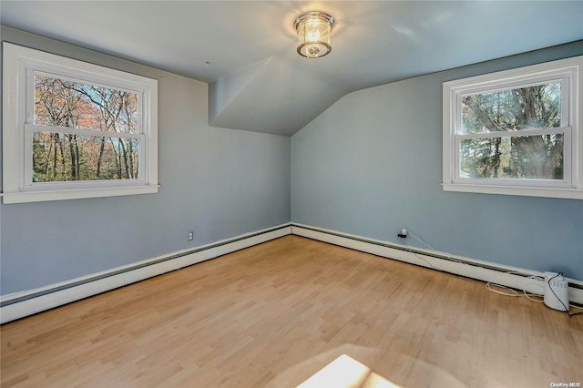 additional living space with light hardwood / wood-style flooring, vaulted ceiling, and a baseboard heating unit